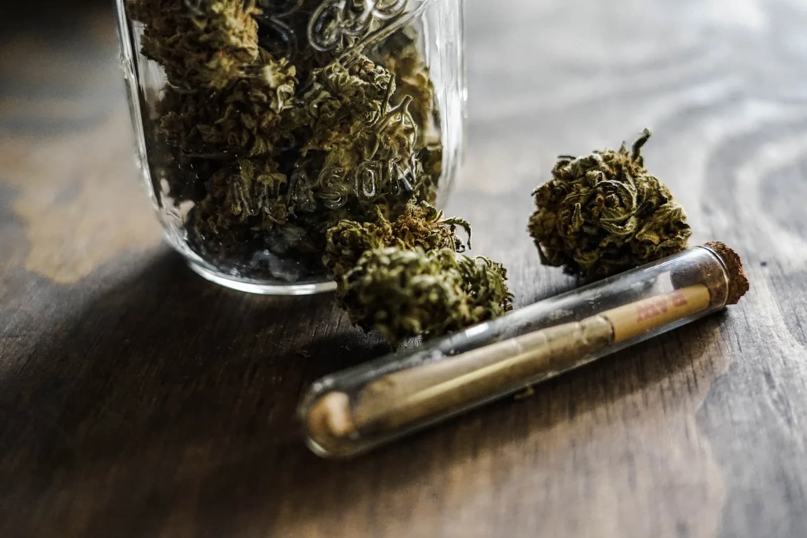 Fleurs de chanvre conservées dans un bocal en verre posé sur une table en bois.