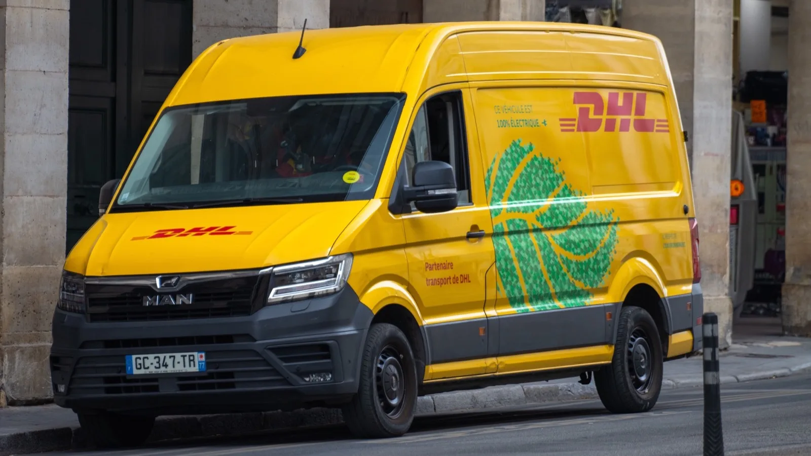 Fourgon DHL en livraison dans une rue parisienne.